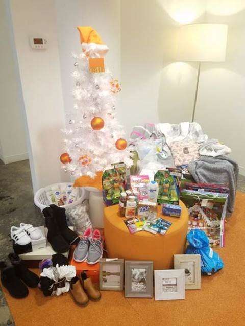 Unwrapped holiday gifts sitting on orange carpet below white and gold Christmas tree