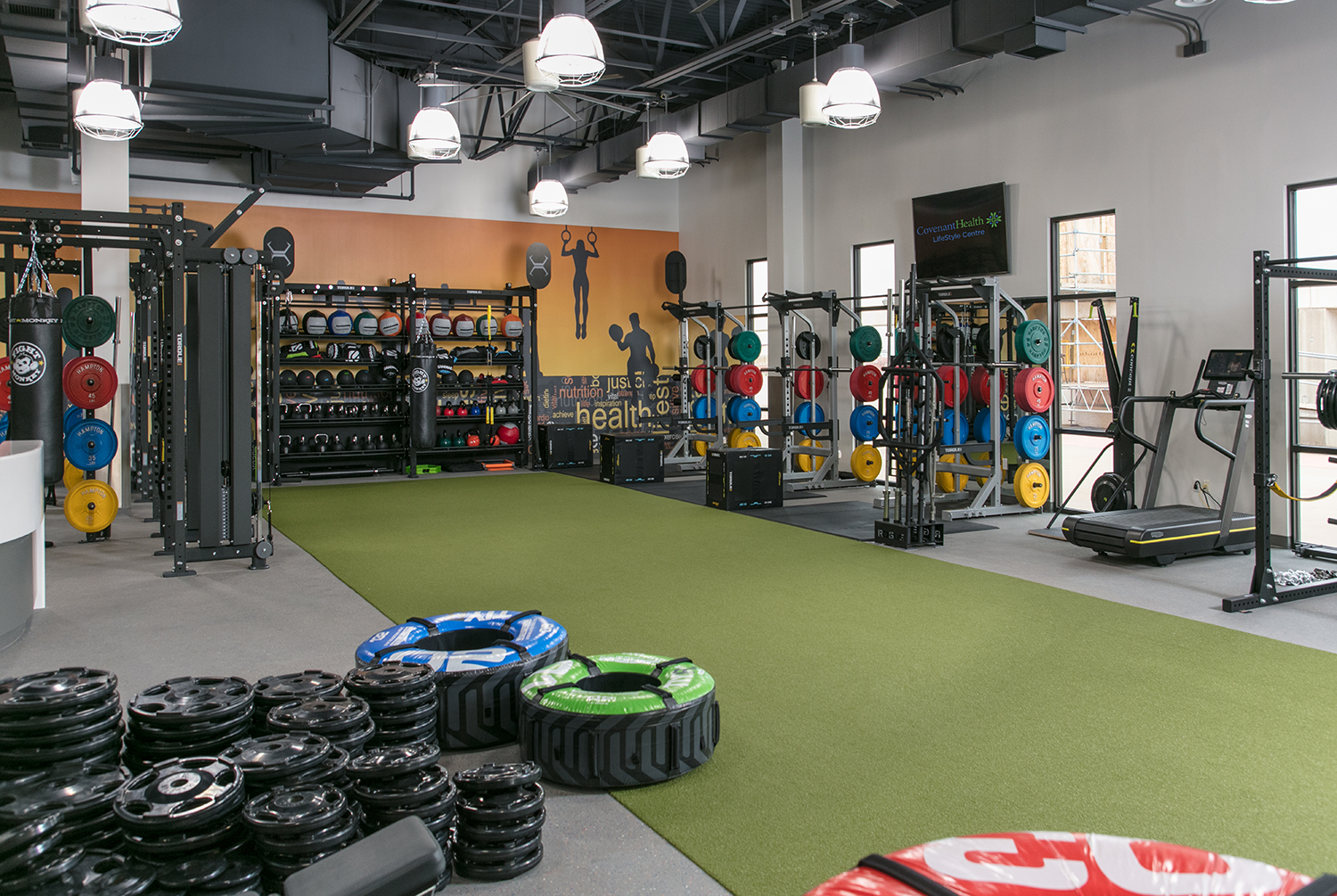 Modern fitness center with stacks of weights, barbells, and treadmill