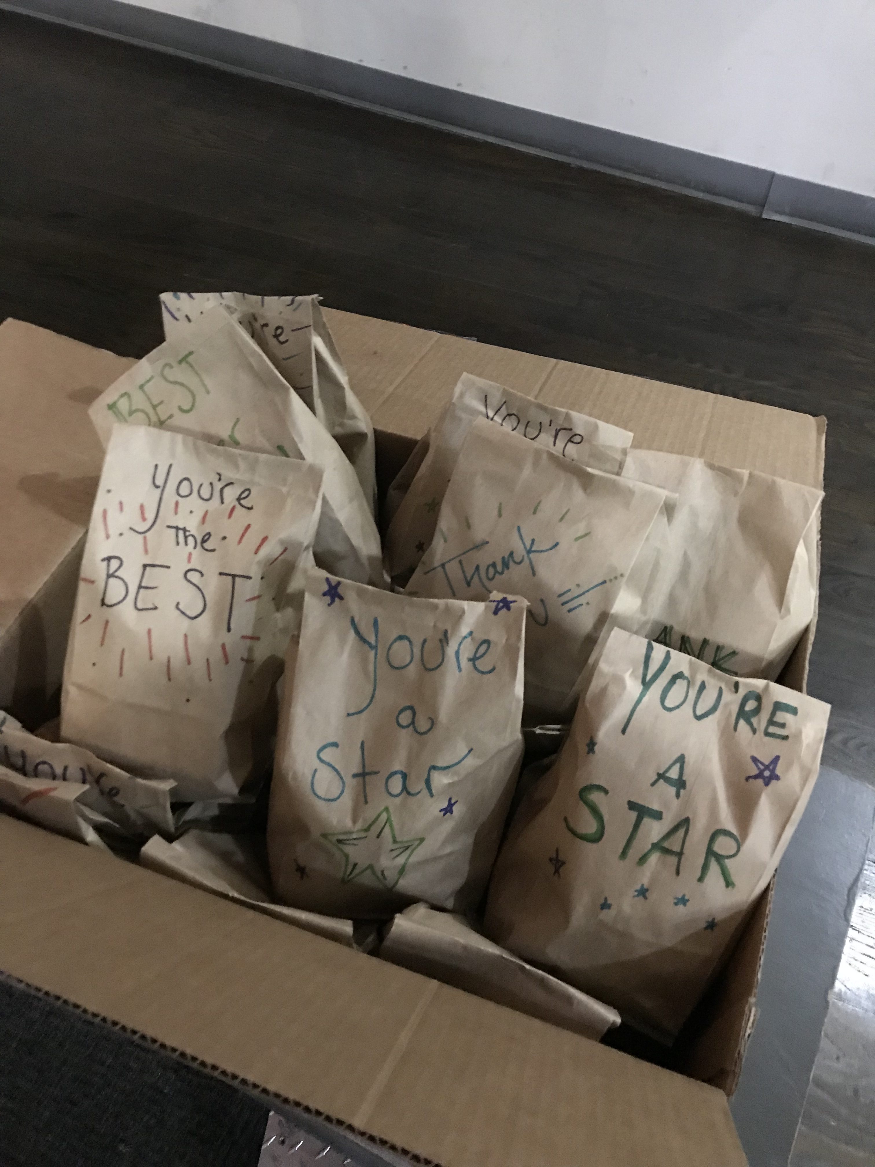 Brown decorated paper bags containing donated Christmas gifts sitting in a cardboard box