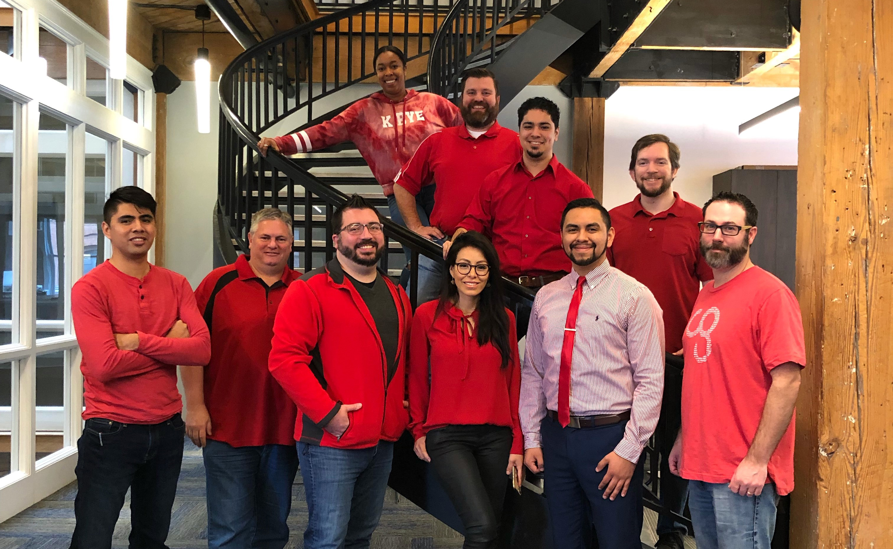 Group of people in red shirts standing in front of stairway and next to window