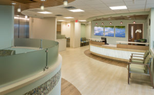 Clean and bright hospital reception area with wood floors, chairs and curved receptionists desk