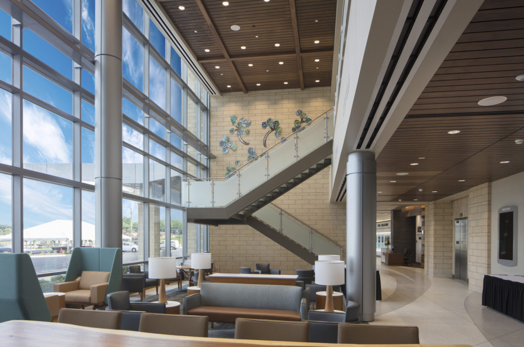 Waiting area with chairs, couches, lamps and tables in front of a staircase