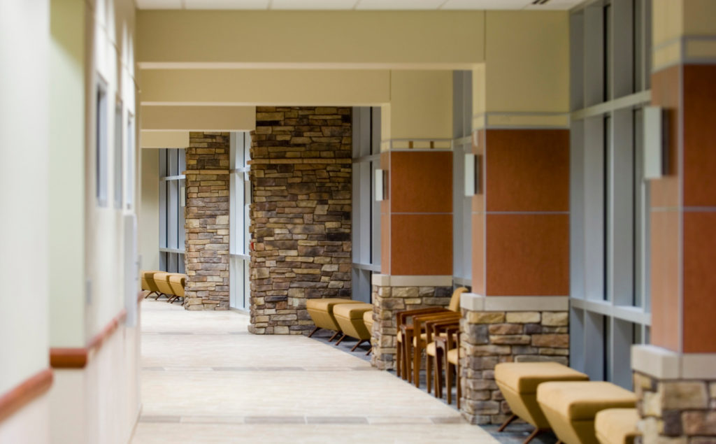 Long hallway with stone columns and chairs along wall