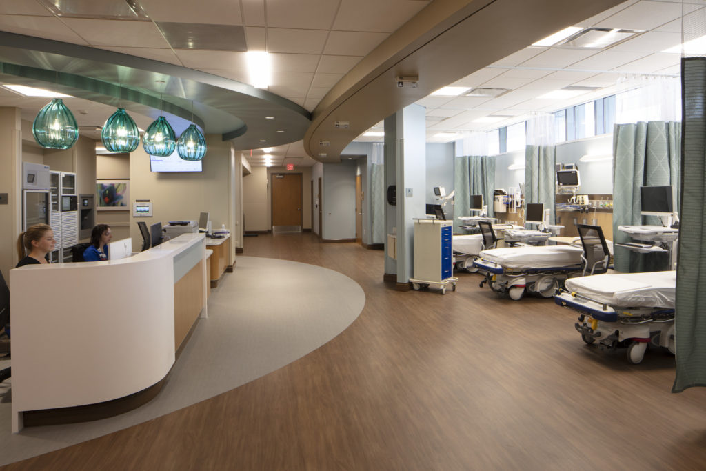 Check-in area of a medical center and three exam tables, chairs, monitors and sets of equipment