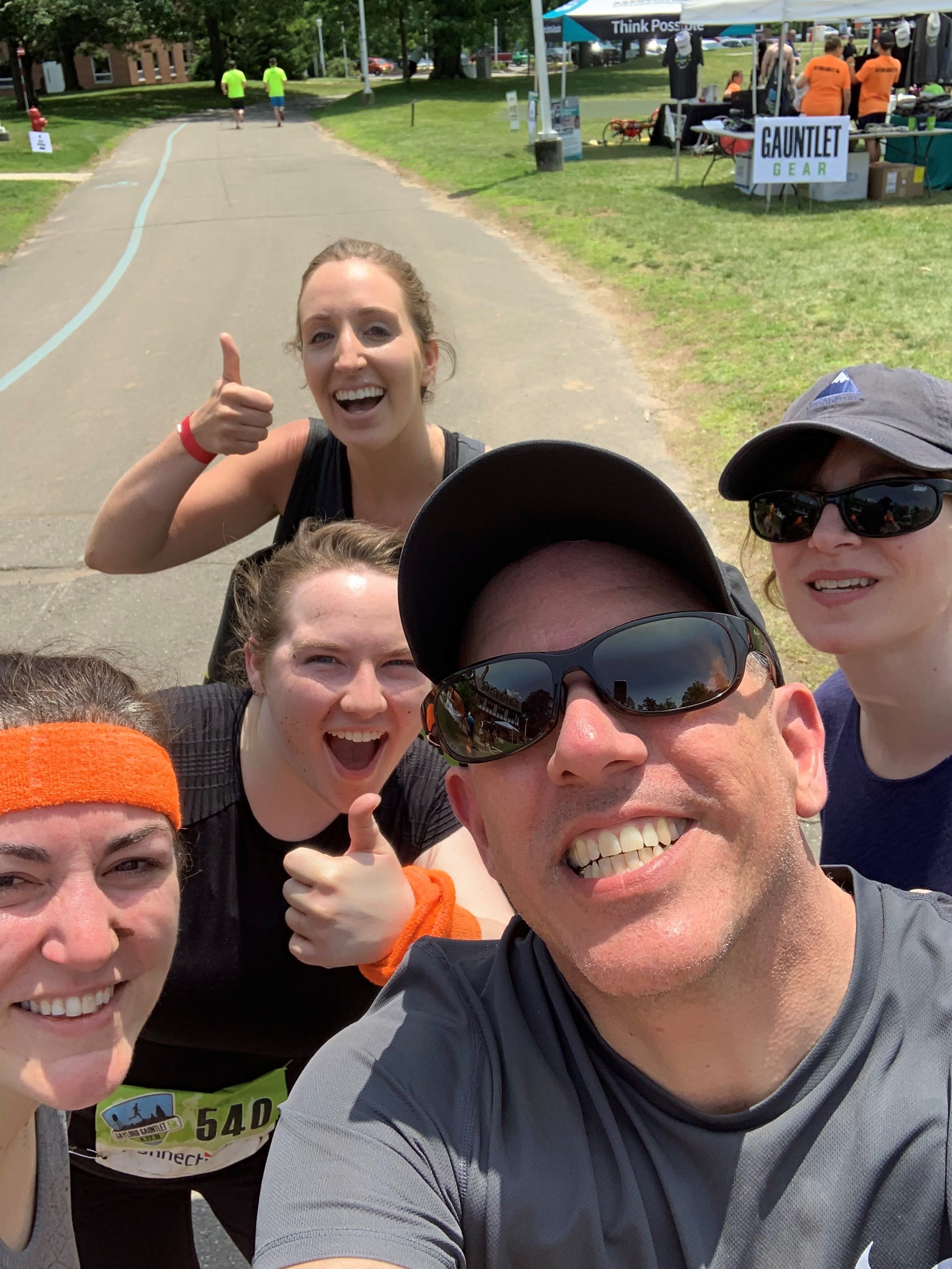Group of four E4H team members in running attire smiling before competing in the Gaylord Gauntlet with other participants in the background