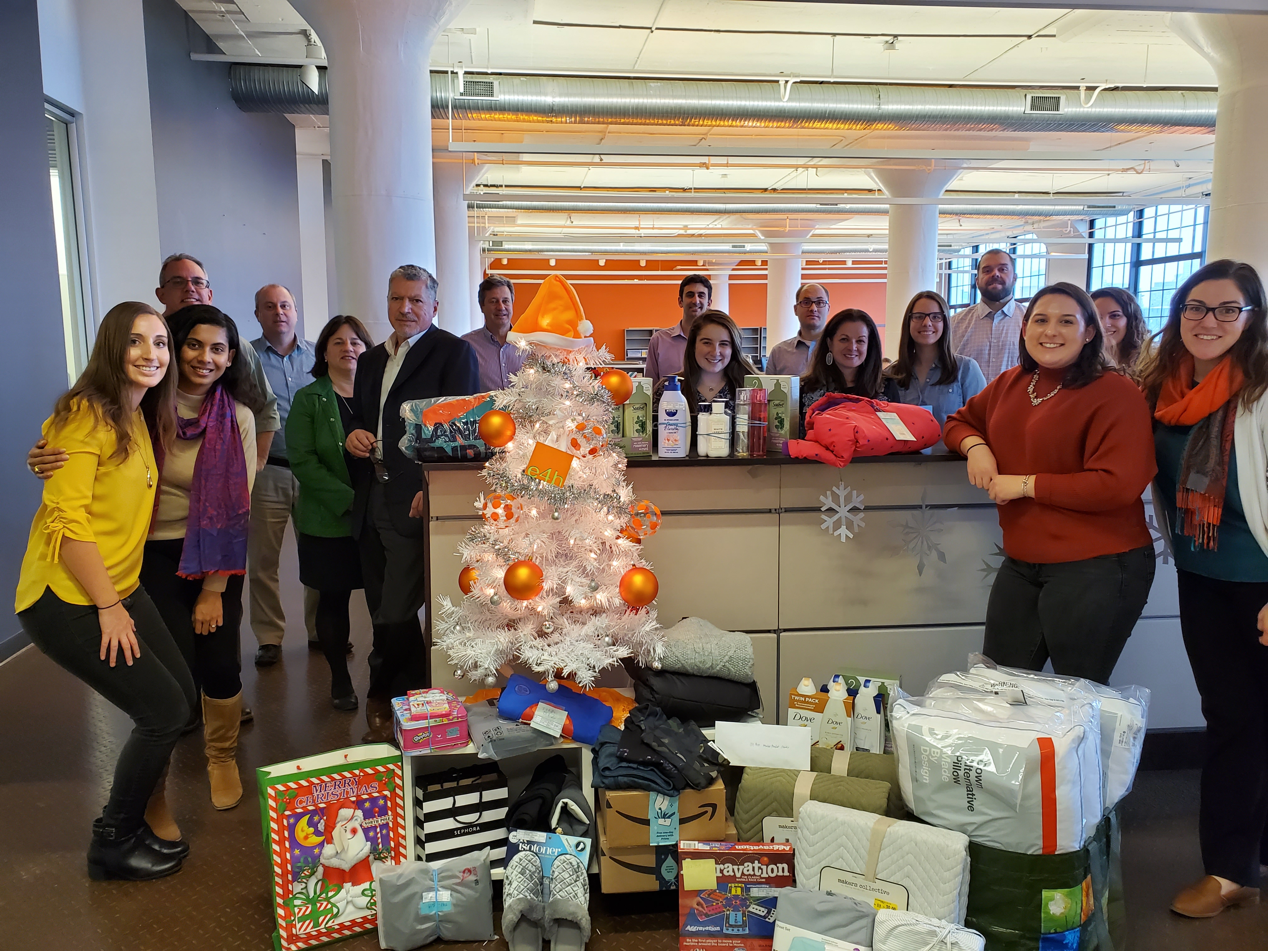 E4H Architecture's Boston team with their decorated holiday tree and wrapped charitable donations underneath