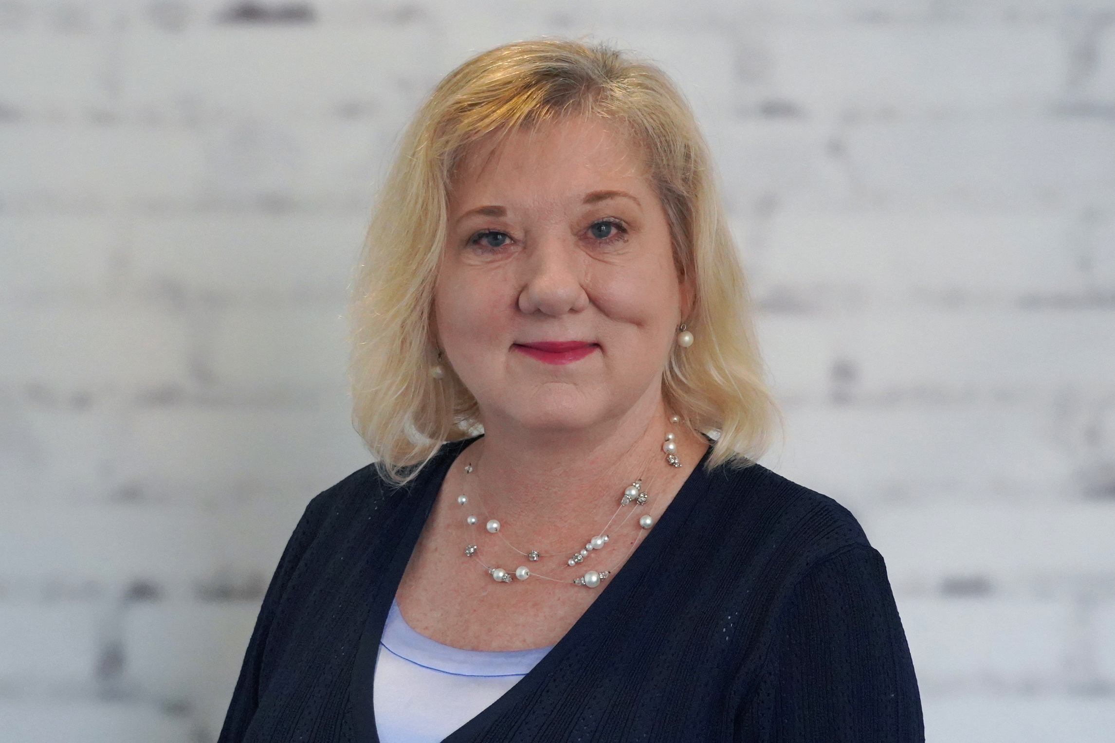 A woman, Kelly Byrd, smiles while wearing professional clothing.